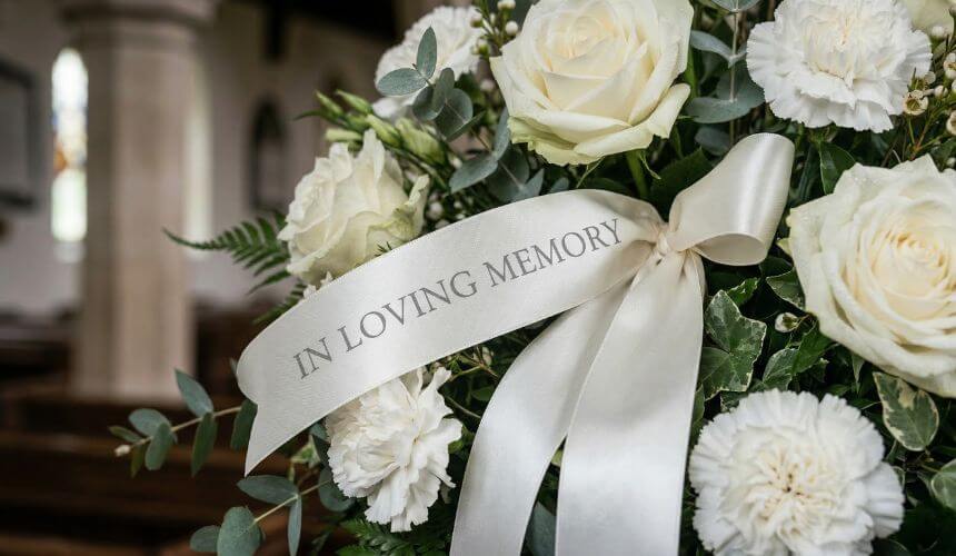 szarfa pogrzebowa przy eleganckim wieńcu z żywych kwiatów